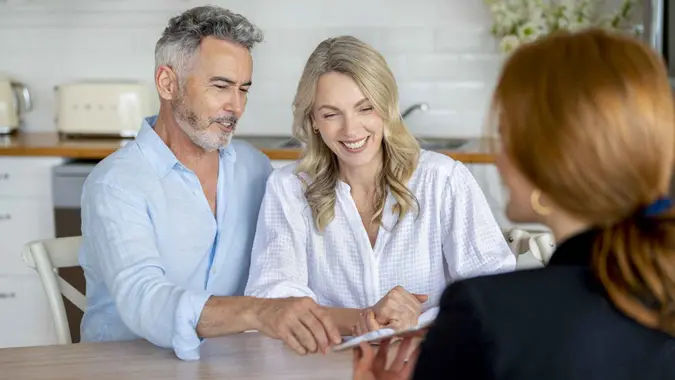 Happy mature couple meeting investments and financial advisor at home.