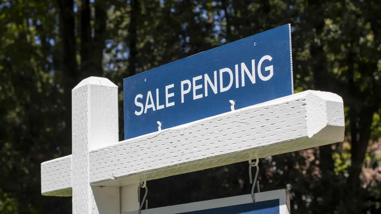 Closeup of a "Sale Pending" real estate sign outside a residential single-family house on the market.