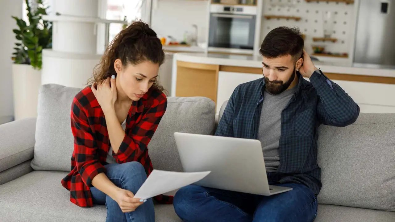 Young couple working on a budget while sitting on sofa in the living room.