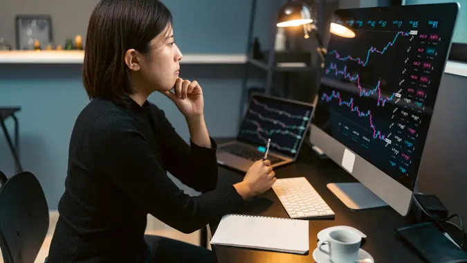 Young woman doing cryptocurrency business trading on her computer at home at nigh stock photo