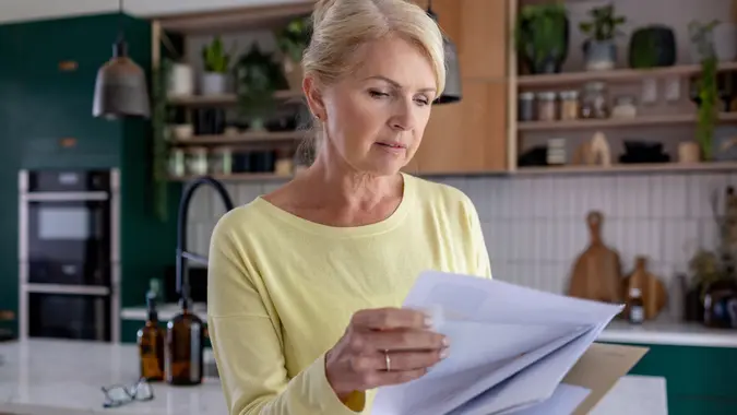 Woman at home reading a letter in the mail stock photo