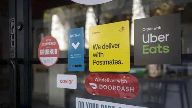 Portland, OR, USA - Apr 18, 2021: Various food delivery service options - DoorDash, Postmates, Uber Eats, Ritual, Caviar, and Grubhub - are seen advertised at the entrance to a restaurant in Portland, Oregon, during the coronavirus pandemic.