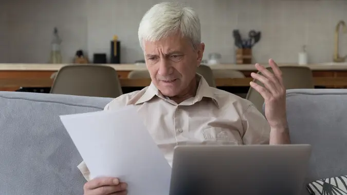 Older man looks dissatisfied while read unpleasant notification from bank stock photo