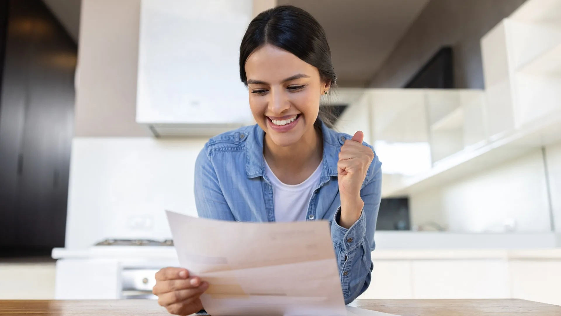 Happy woman at home reading a letter in the mail stock photo