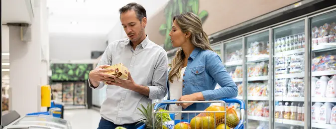 Happy Latin American couple buying groceries at the supermarket and using a shopping cart - lifestyle concepts.
