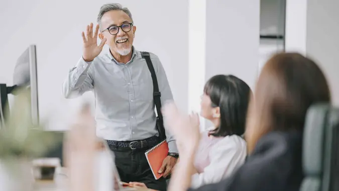 working asian chinese senior colleague back to work with face mask greeting on each other in office morning.