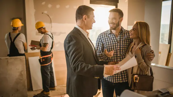 Young happy couple talking to their investor about housing plan inside of an apartment.