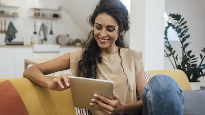 Portrait of a happy young woman using tablet at home stock photo