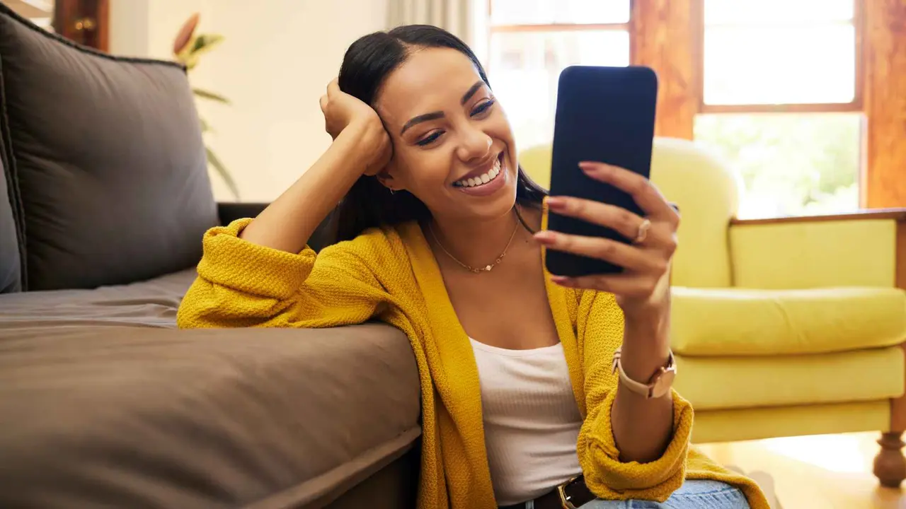 Woman smiling at her cellphone at home.