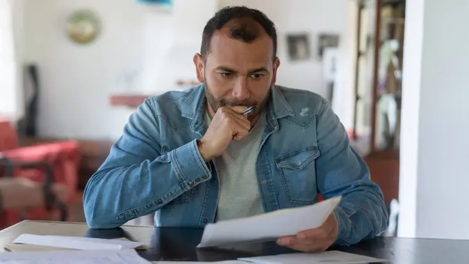 Low income man checking his home finances and looking worried stock photo