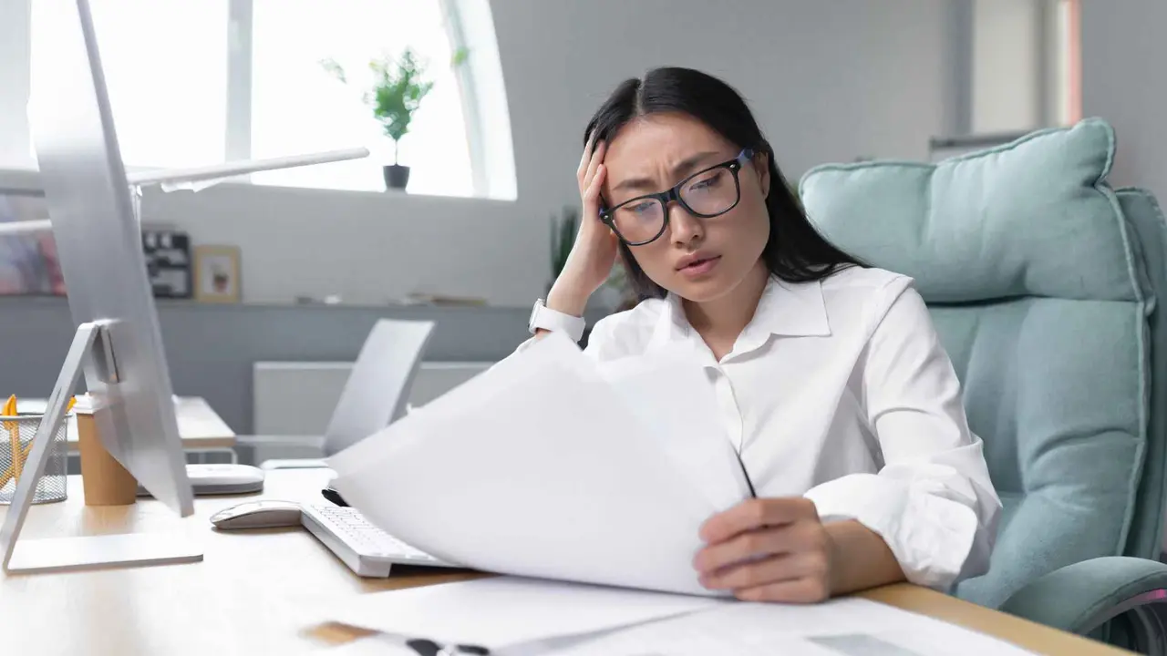 Business woman behind paper work, tired and frustrated, working in office, female employee in bra looking at documents and financial reports.