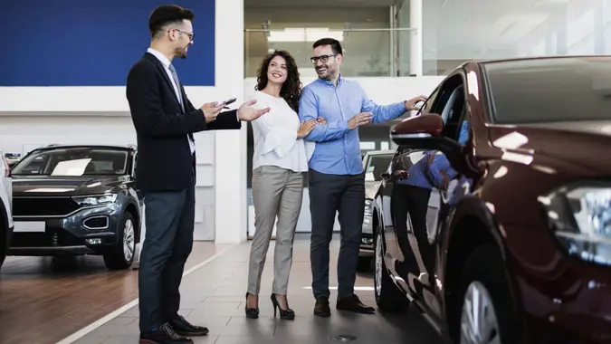 Middle age couple choosing and buying car at car showroom.