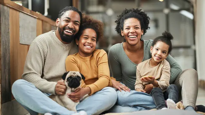 Happy black parents with their small girls and a dog spending time at home.