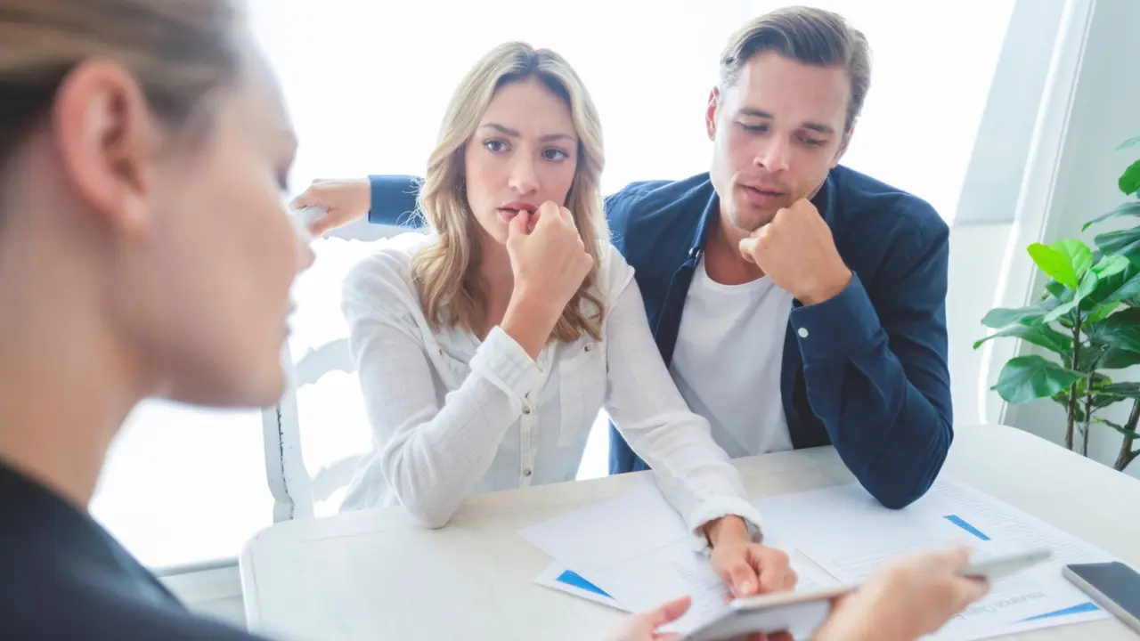 Real estate agent with couple looking through documents.