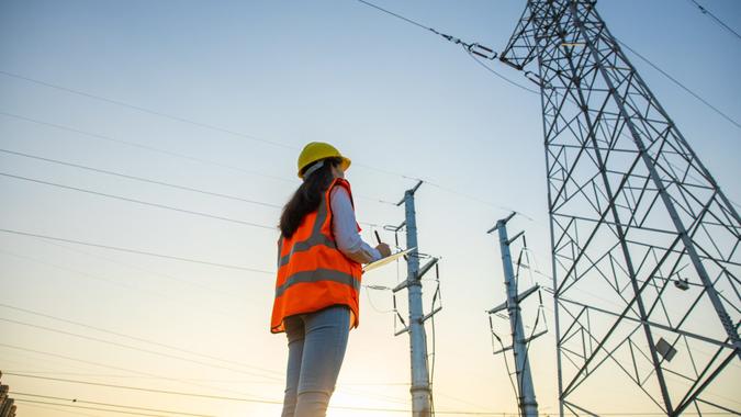 Women electrical engineer while working near to high voltage tower.