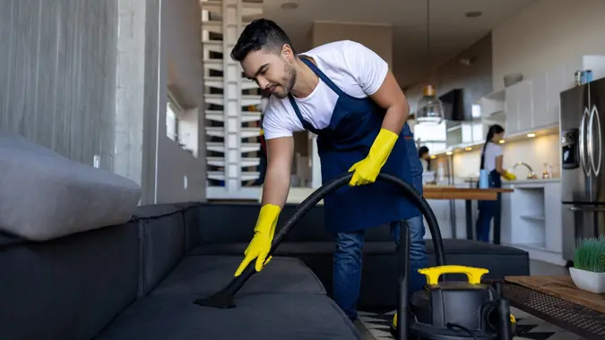 Professional cleaner vacuuming a sofa stock photo