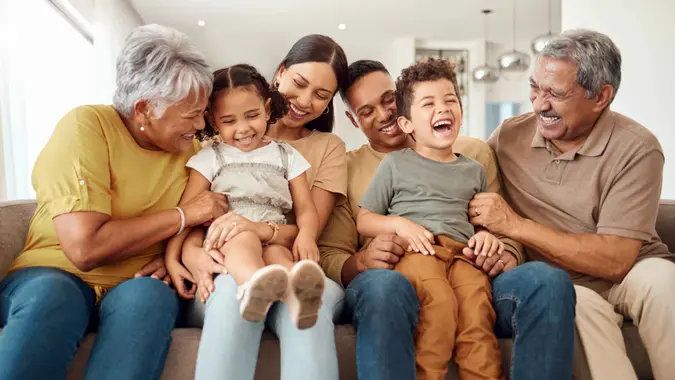 A family smiles as they sit together on a couch.