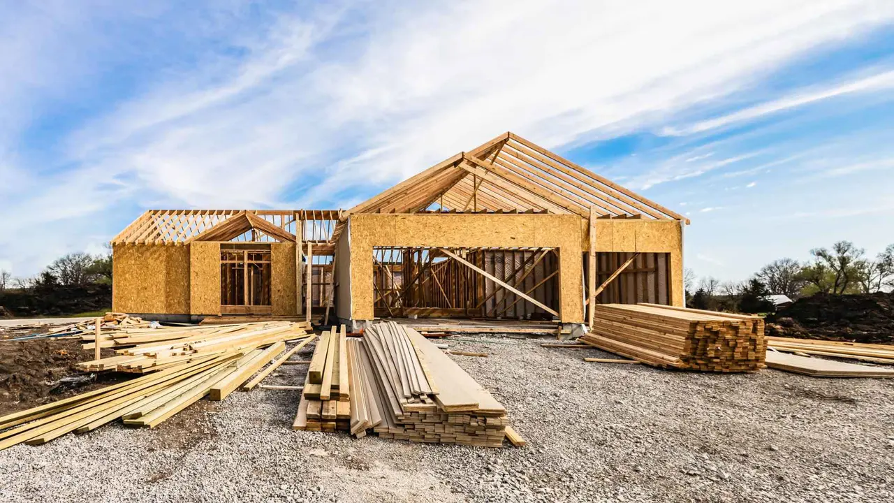 New house under construction, front view from garage door entry with clouds in blue sky.