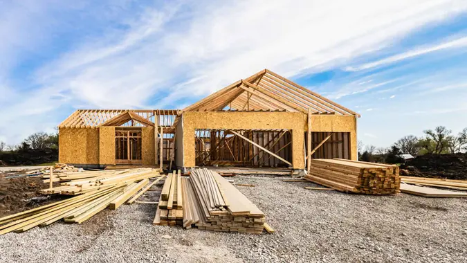 New house under construction, front view from garage door entry with clouds in blue sky.
