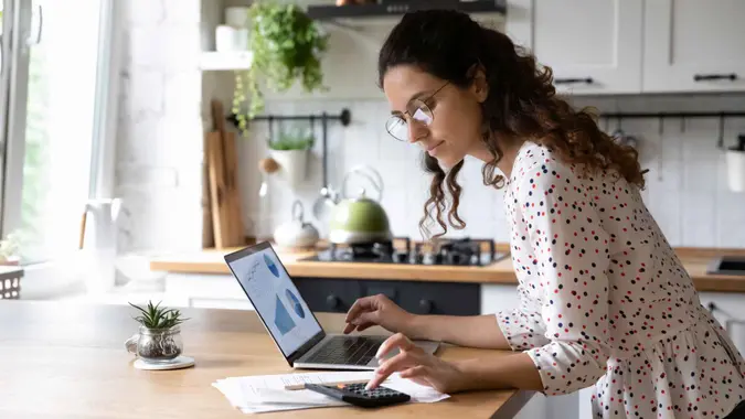 A woman looks at her computer and goes over her finances.