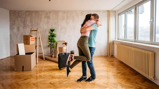 Joyful young couple embracing in their new empty apartment.