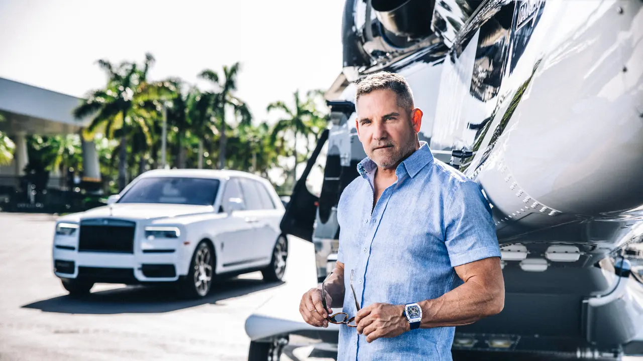 Grant Cardone standing in front of a car.