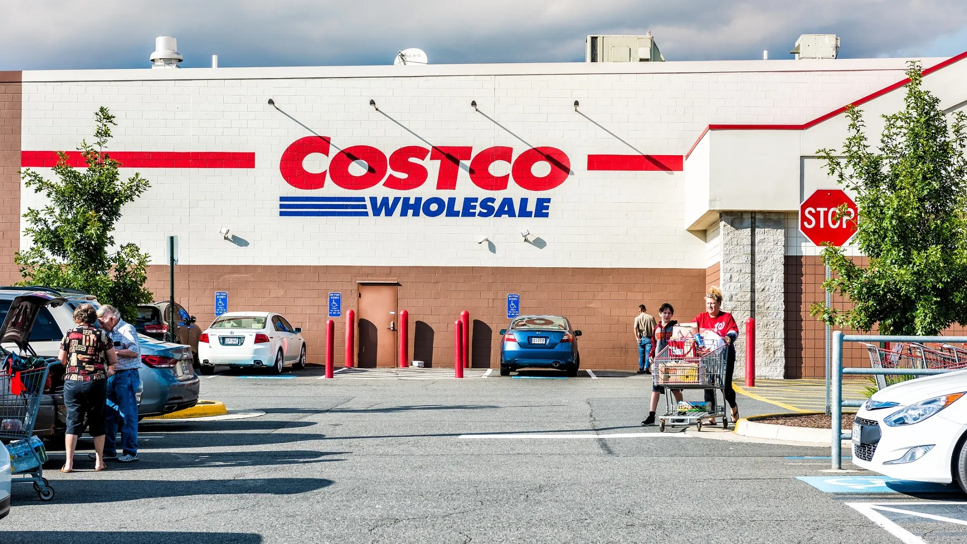 People with shopping carts filled with groceries goods, products walking out of Costco store in Virginia in parking car lot stock photo