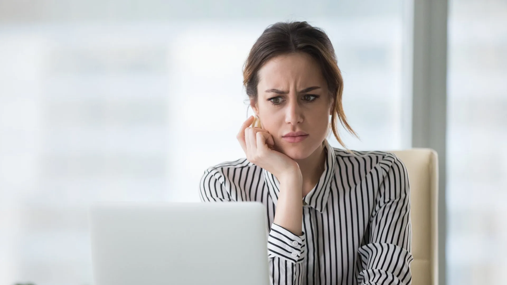 Confused businesswoman annoyed by online problem, spam email or fake internet news looking at laptop, female office worker feeling shocked about stuck computer, bewildered by scam message or virus.