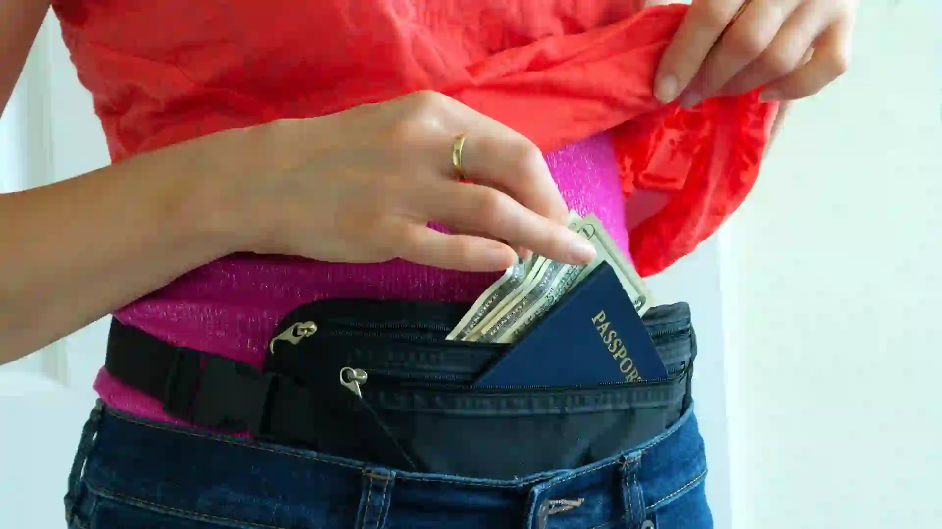 Woman getting cash and passport from hidden travel money belt that she has under her clothes to protect herself from pickpocket thieves and credit card scanners safely transporting documents in transit.