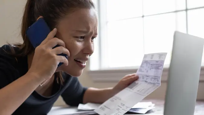 Woman is very stressed handling her bills on the computer.