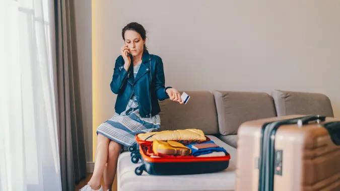 Young woman in hotel room trying to call the bank for customer support.