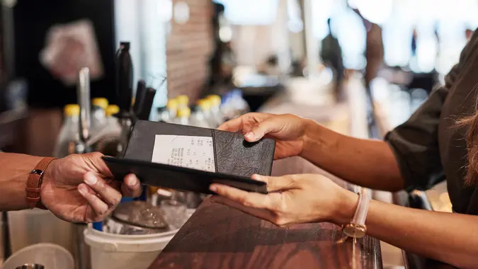 Hands with bill, food service and people in restaurant, customer with receipt and payment with cashier or waiter.