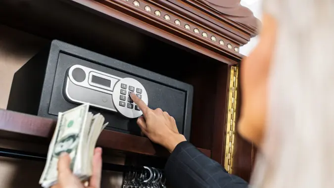 Woman opening the safe to put the money in it.
