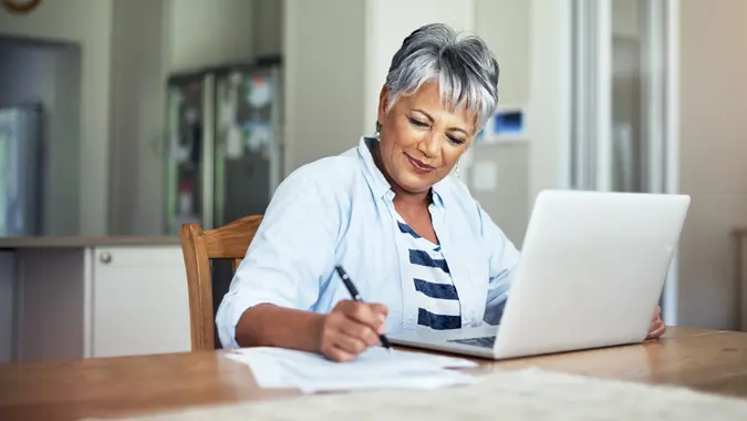 A senior woman using a laptop to do the household finances.