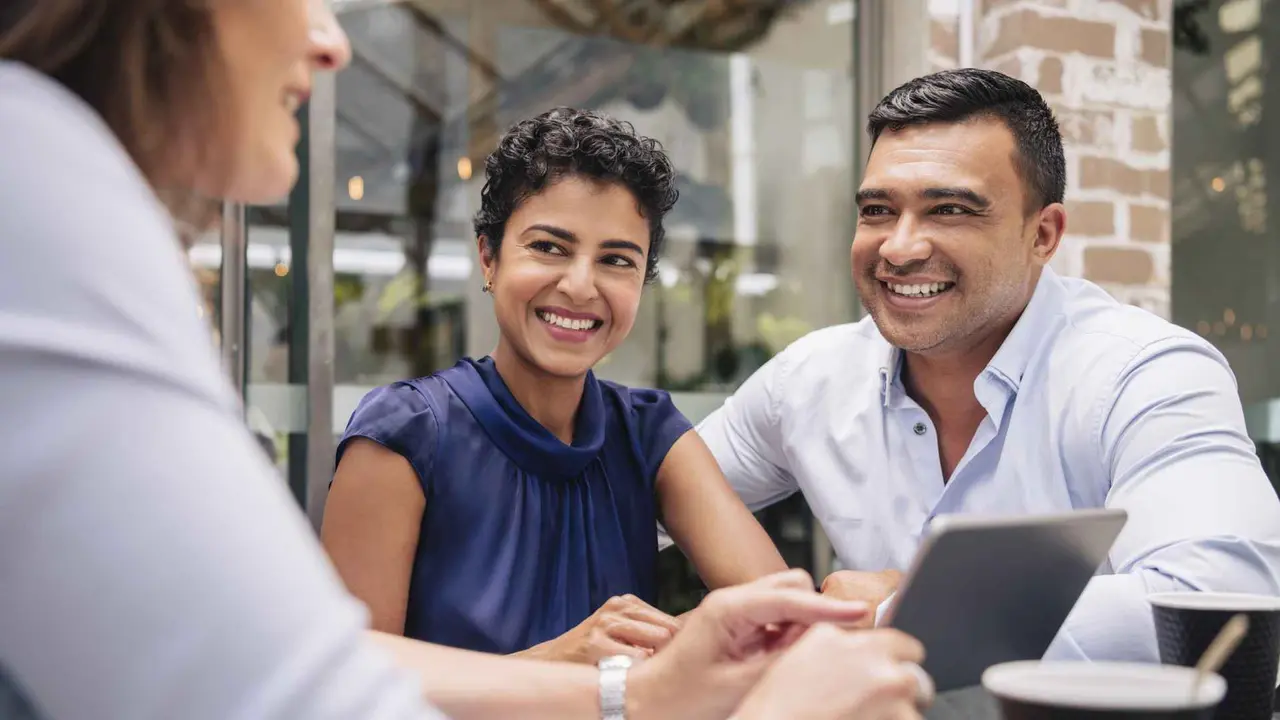 A couple smiles and looks happy during a meeting with their adviser.