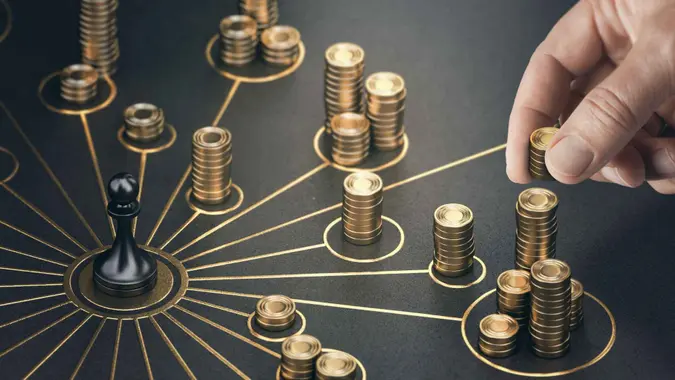 Man puting golden coins on a board representing multiple streams of income.