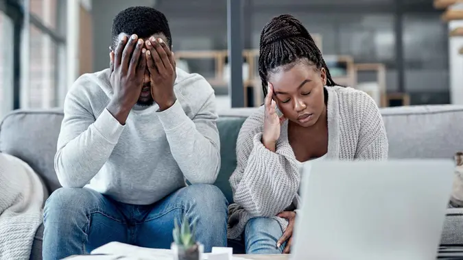 Shot of a young couple looking stressed while working on their finances at home.