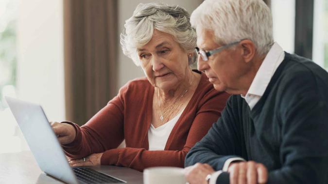 Laptop, finance and investment with a senior couple planning their retirement together in their home living room.