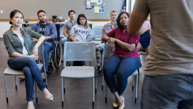 The diverse group of military veterans listen to the talk given by an unrecognizable speaker.