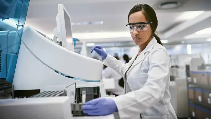 Shot of a young woman using a machine to conduct a medical test in a laboratory.