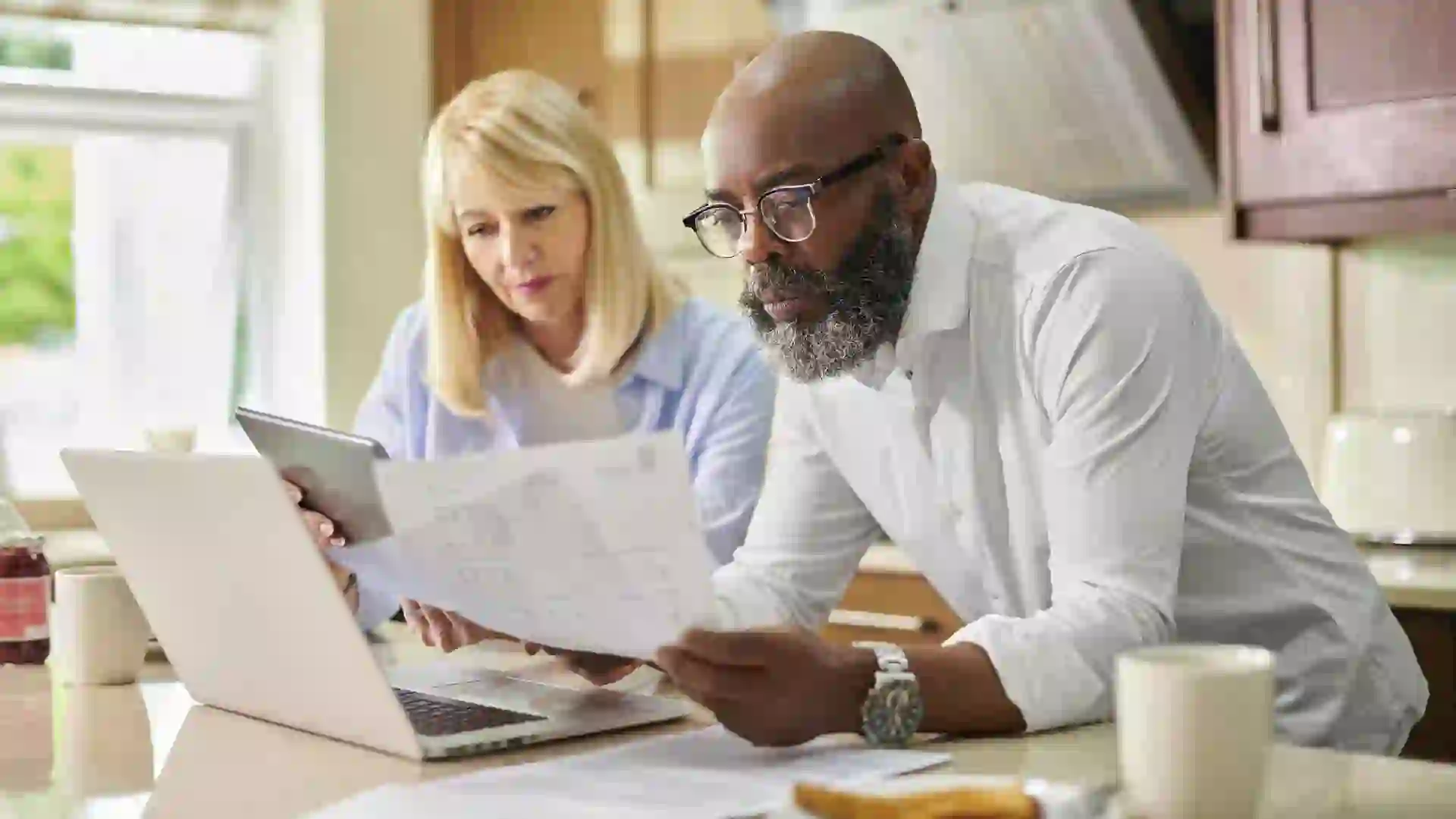 An older couple goes over papers together in their kitchen.