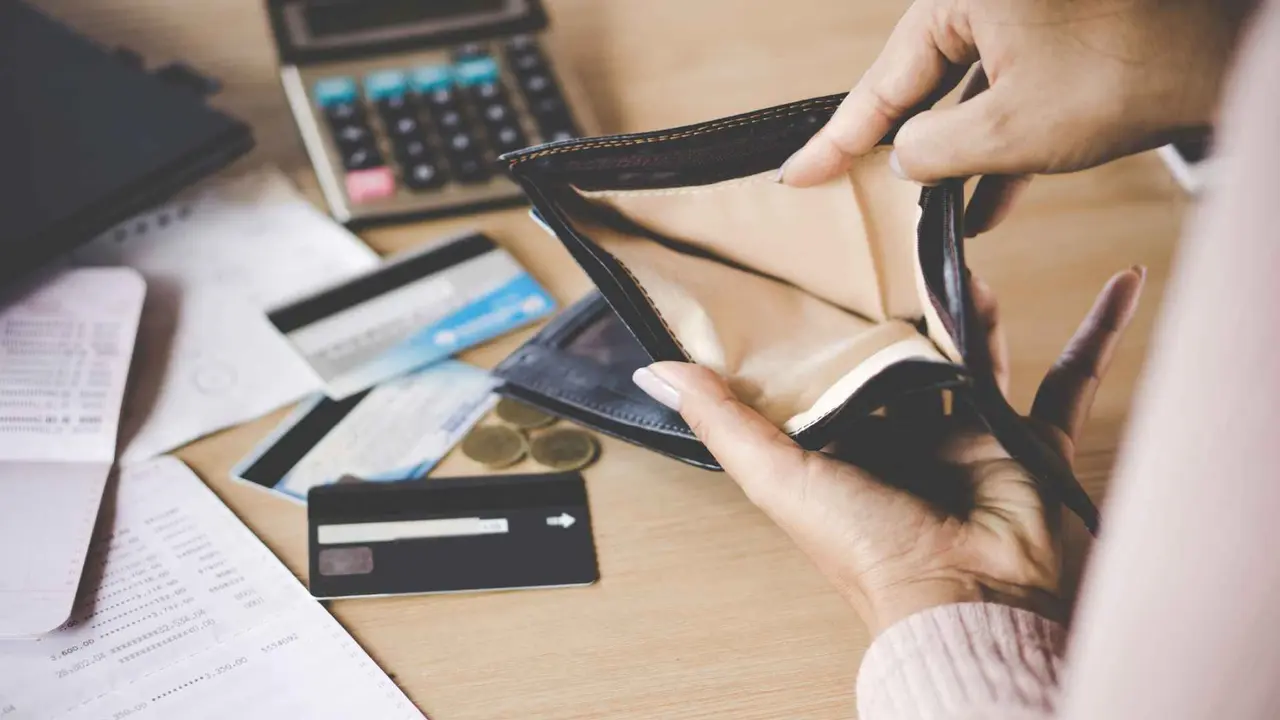 Poor Asian woman has problems with credit card bankruptcy after payday and opens empty wallet in hand looking for money.