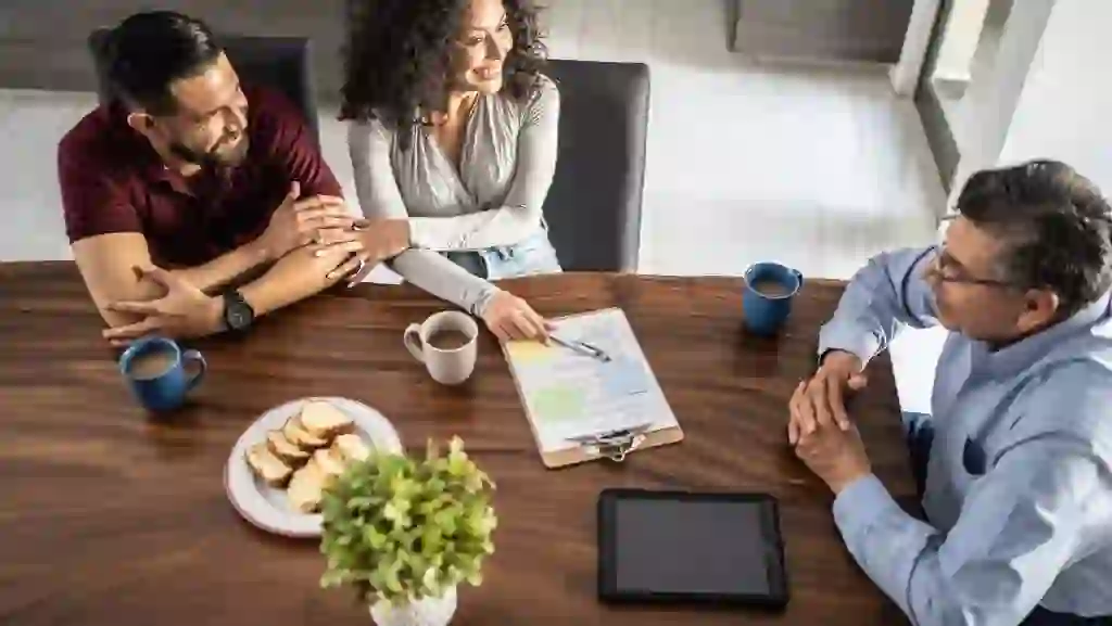 Mid adult couple having a meeting with real estate agent (or financial advisor) at house stock photo