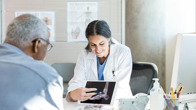 Orthopedic surgeon uses x-ray displayed on tablet to help patient stock photo