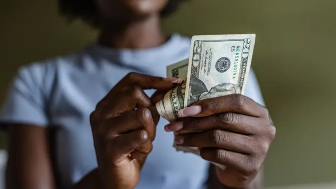 African American woman holding and counting dollars.