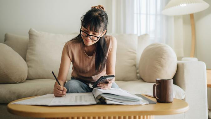 Woman writing in a notebook, evaluating finances