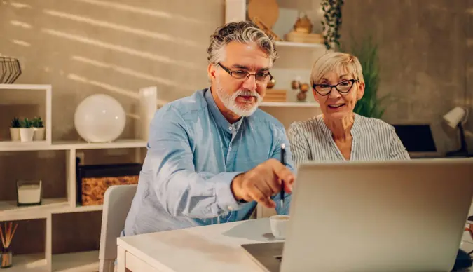 Senior couple sitting at the table at home while online shopping with a laptop and a credit card.