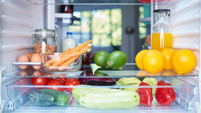 Opened fridge from the inside full of vegetables, fruits and other groceries.