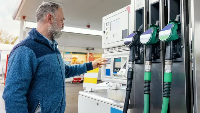 A man at the gas station filling the tank of his car with diesel to the top level before a long journey as fuel prices is going up stock photo
