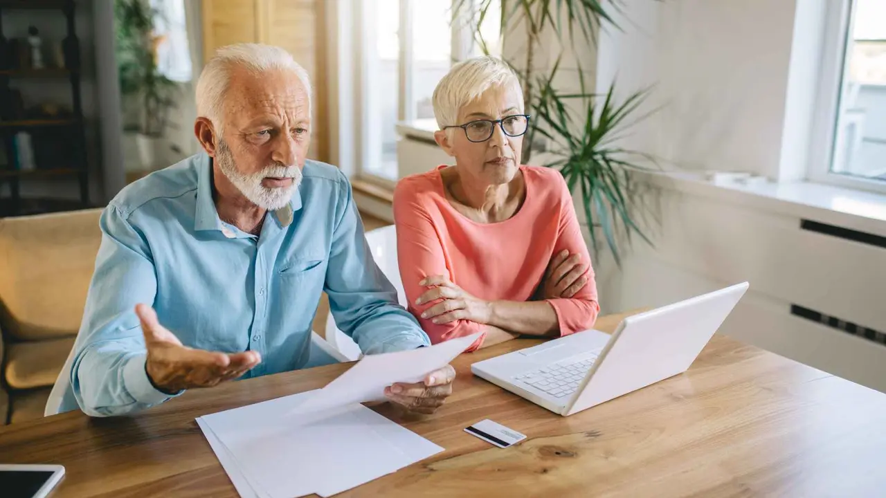 Senior couple having a hard time at home, calculating incoming bills and debt.